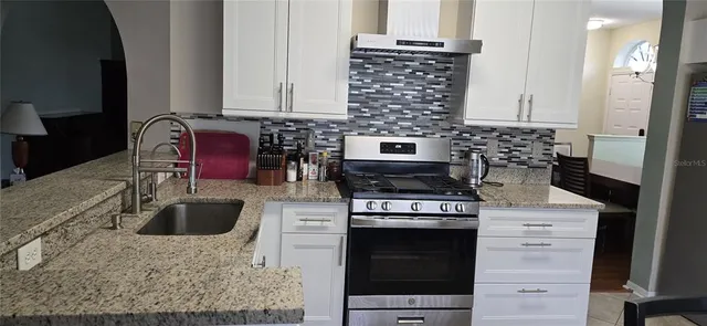 a kitchen with granite countertop a stove sink and cabinets
