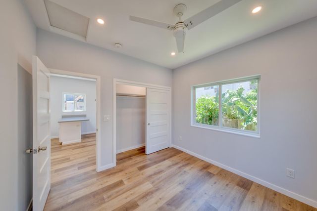 an empty room with wooden floor cabinet and windows