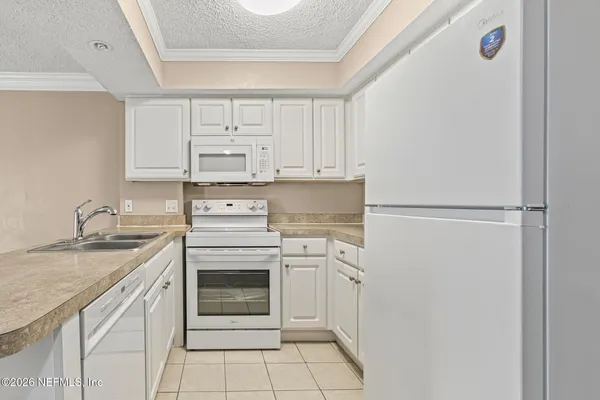 a kitchen with white cabinets and white appliances
