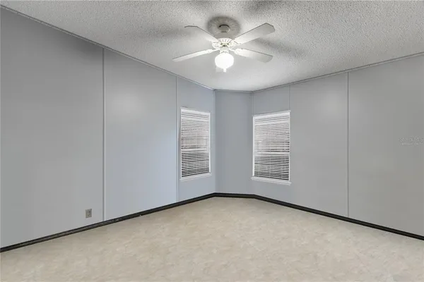 an empty room with windows and chandelier fan