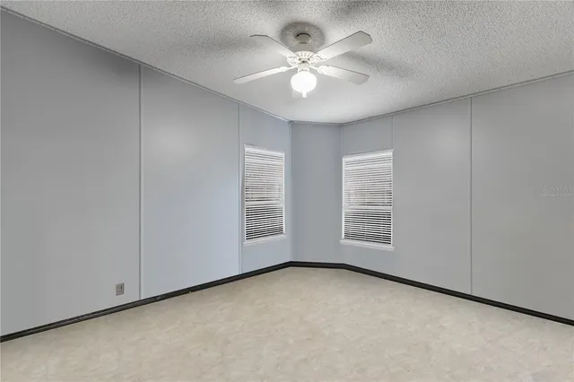 an empty room with windows and chandelier fan