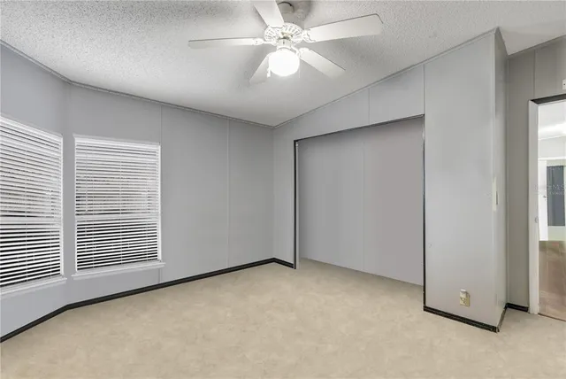 an empty room with a ceiling fan and a window