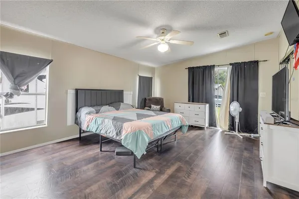 a spacious bedroom with a bed a chandelier and a flat screen tv