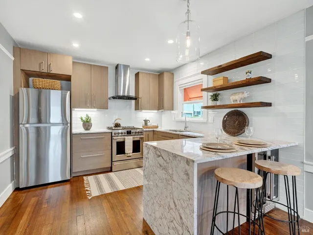 a kitchen with stainless steel appliances granite countertop a refrigerator a stove and a wooden floors