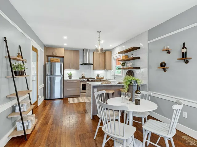 a kitchen with stainless steel appliances granite countertop a dining table chairs and white cabinets