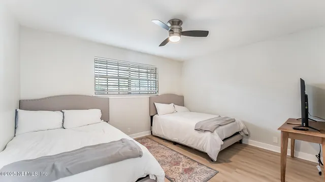 a bedroom with a bed a couch and a flat tv screen on a dresser