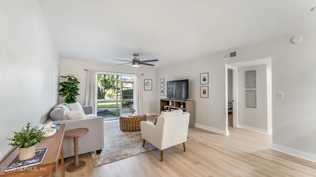 a living room with furniture a large window and wooden floor
