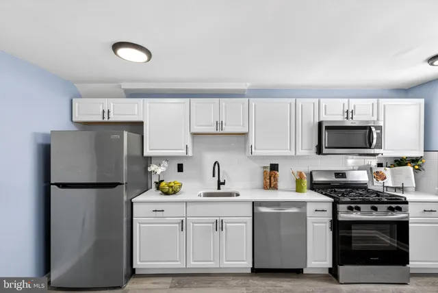 a kitchen with a refrigerator sink and white cabinets