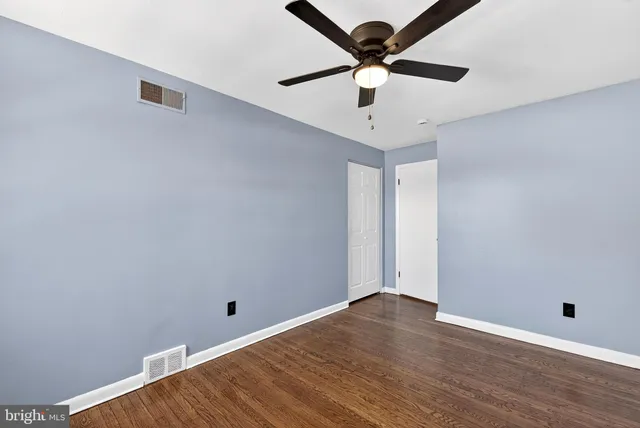 an empty room with wooden floor and ceiling fan