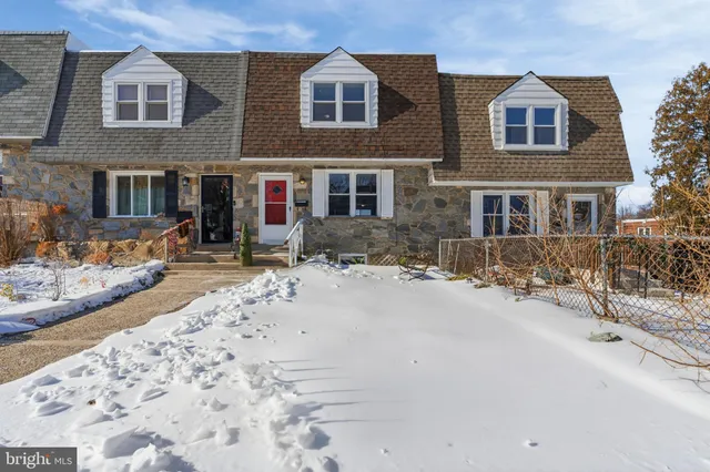 a front view of a house with a yard covered with snow