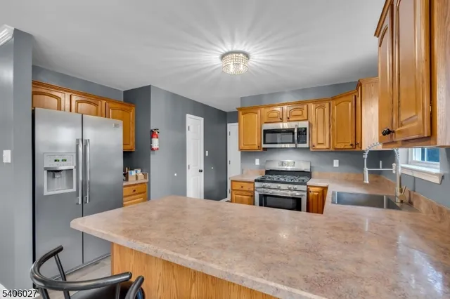 a kitchen with stainless steel appliances granite countertop a stove a refrigerator a oven a sink with island and chairs