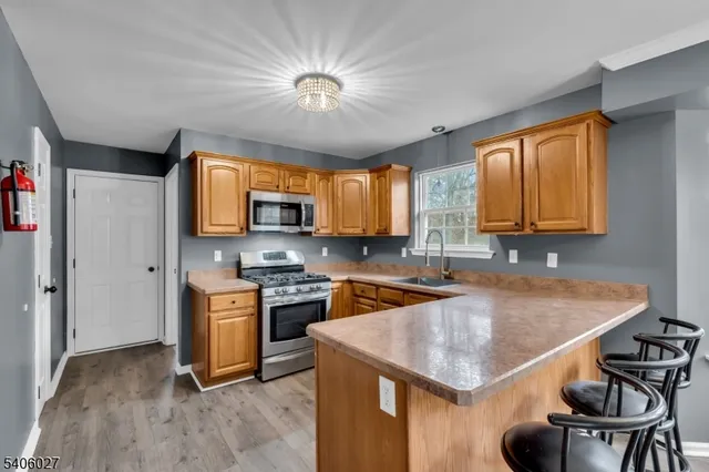 a kitchen with stainless steel appliances granite countertop a sink dishwasher a stove and a refrigerator with wooden floor