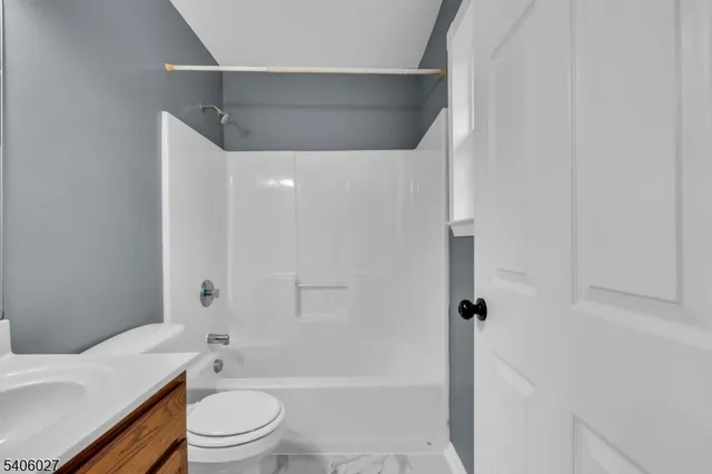 a bathroom with a granite countertop bathtub shower sink vanity and toilet