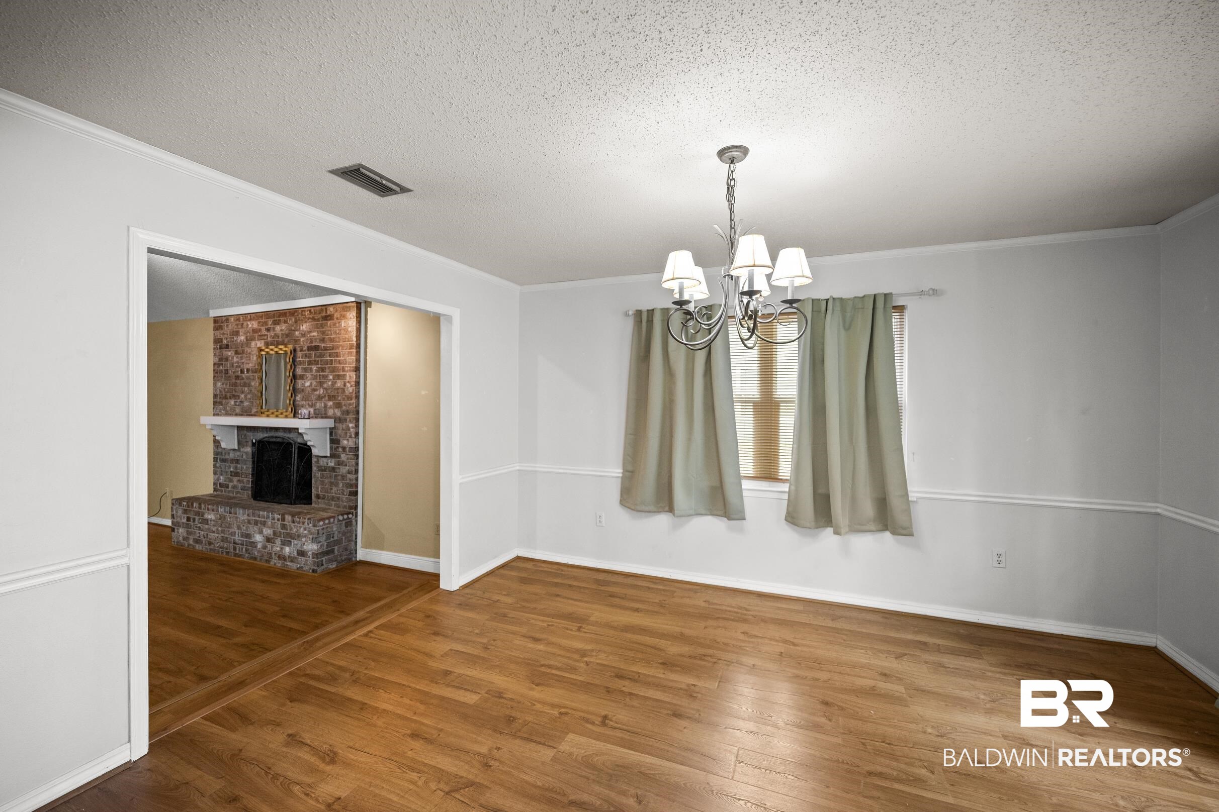 123 Dunbar Loop Daphne, AL 36526 - Photo 6 of 33 Unfurnished dining area featuring hardwood / wood-style flooring, a textured ceiling, a chandelier, a fireplace, and ornamental molding