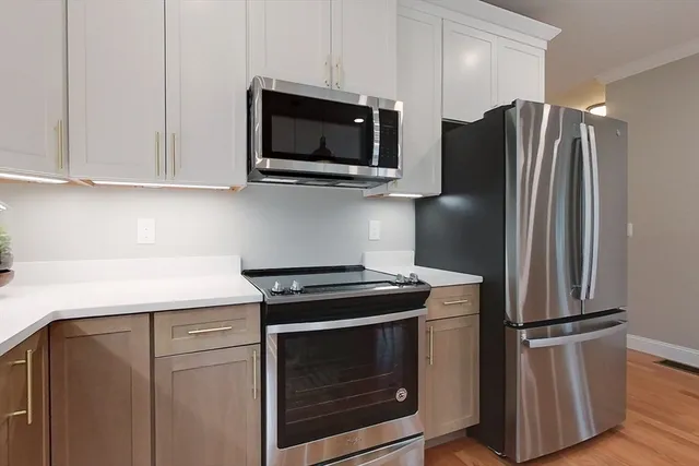 a kitchen with stainless steel appliances white cabinets white stove a microwave and a refrigerator
