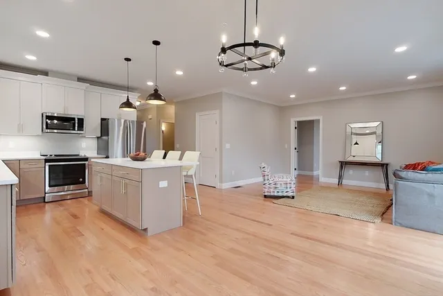 a kitchen with stainless steel appliances kitchen island granite countertop a sink and dishwasher a stove top oven with wooden floor