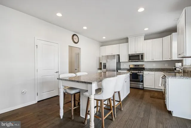 a kitchen with stainless steel appliances granite countertop a sink stove cabinets and refrigerator