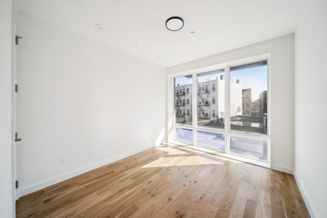 12 Broome Street, Unit 3B Brooklyn, NY 11222 - Photo 2 of 14 an empty room with wooden floor and windows