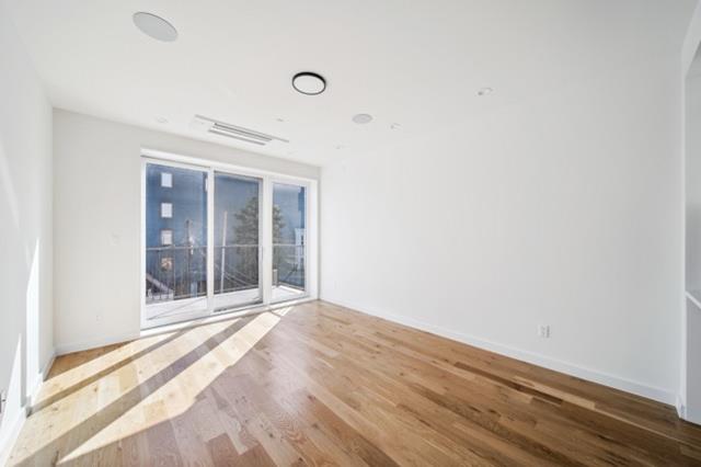 12 Broome Street, Unit 3B Brooklyn, NY 11222 - Photo 3 of 14 a view of an empty room with wooden floor and windows