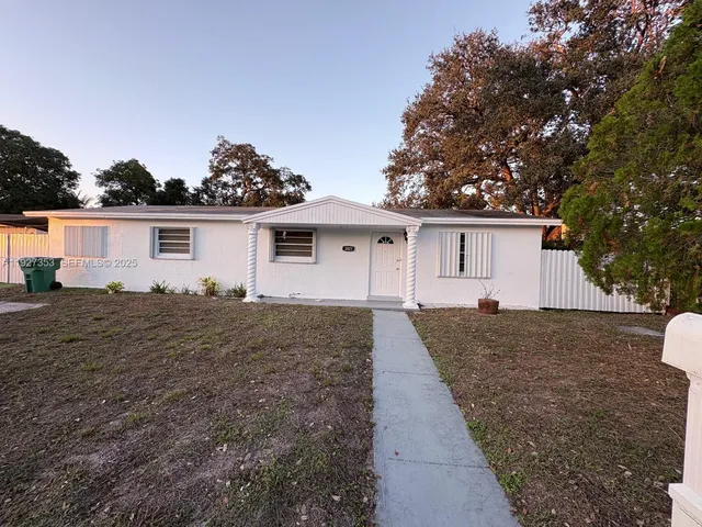 a front view of house with yard and trees in the background
