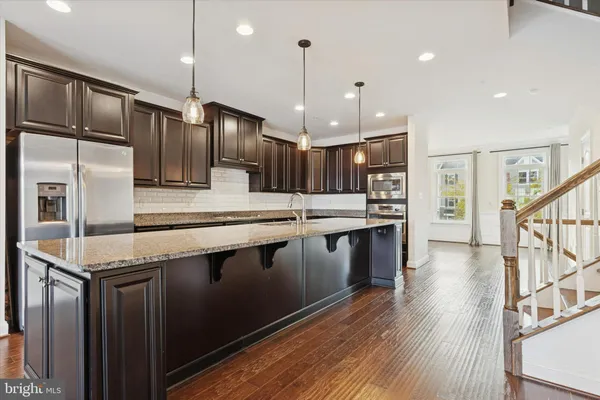 a kitchen with stainless steel appliances granite countertop a sink refrigerator and cabinets