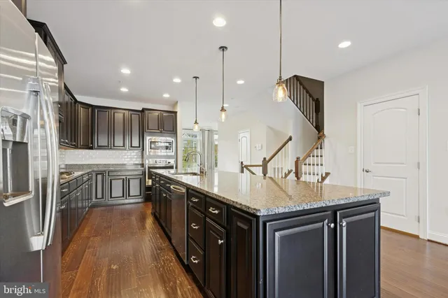 a kitchen with stainless steel appliances granite countertop a sink a stove and a wooden floors