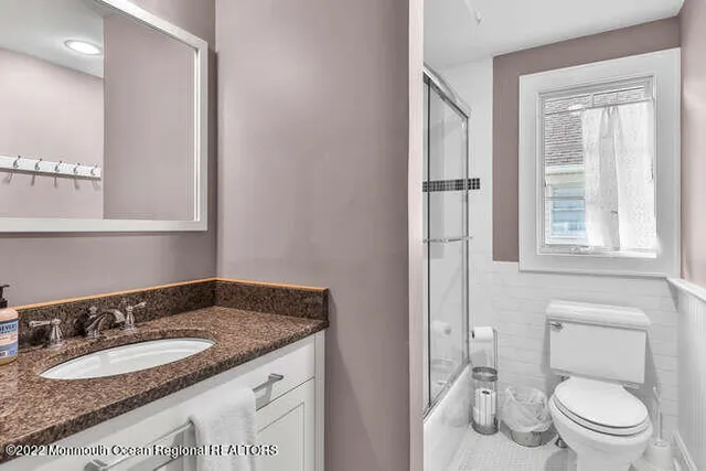 a bathroom with a granite countertop sink and a toilet
