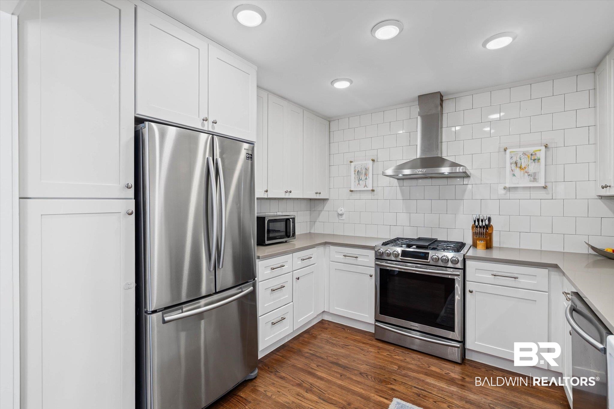 4310 The Cedars Avenue Mobile, AL 36608 - Photo 9 of 32 Kitchen with appliances with stainless steel finishes, white cabinetry, wall chimney range hood, dark wood-style floors, and backsplash
