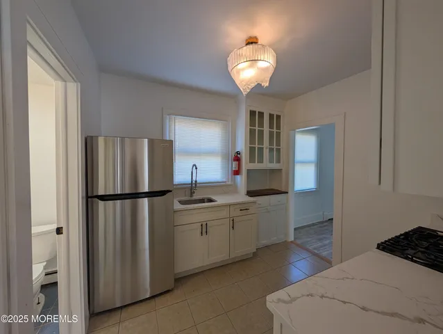 a kitchen with white cabinets and refrigerator