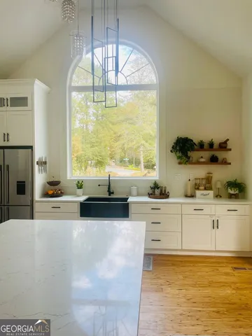 a large white kitchen with kitchen island a large window a sink and stainless steel appliances