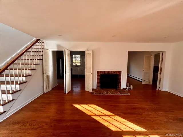 a view of an empty room with wooden floor and windows