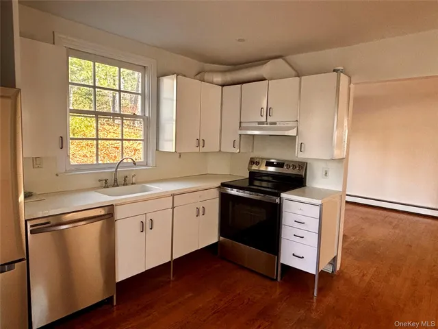 a kitchen with granite countertop a sink cabinets and wooden floor