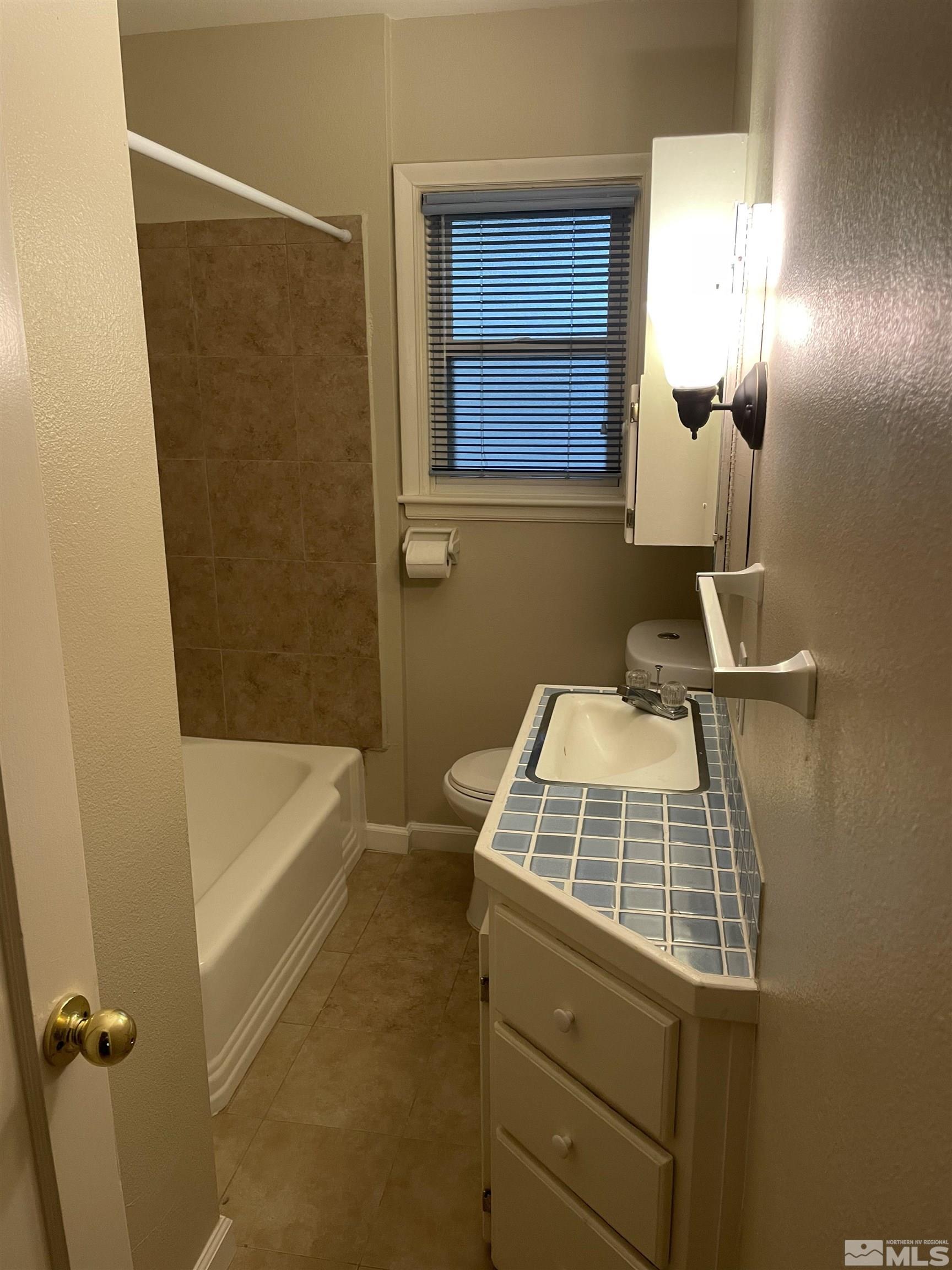 923 University Terrace Reno, NV 89503 - Photo 8 of 13 a bathroom with a sink a toilet a window and vanity