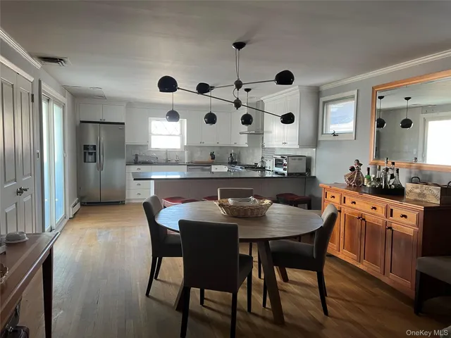 a dining room with stainless steel appliances kitchen island granite countertop a table chairs a sink and dishwasher