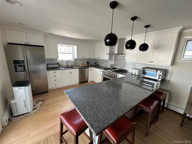 a kitchen with stainless steel appliances granite countertop a kitchen island a stove a sink a dining table and chairs