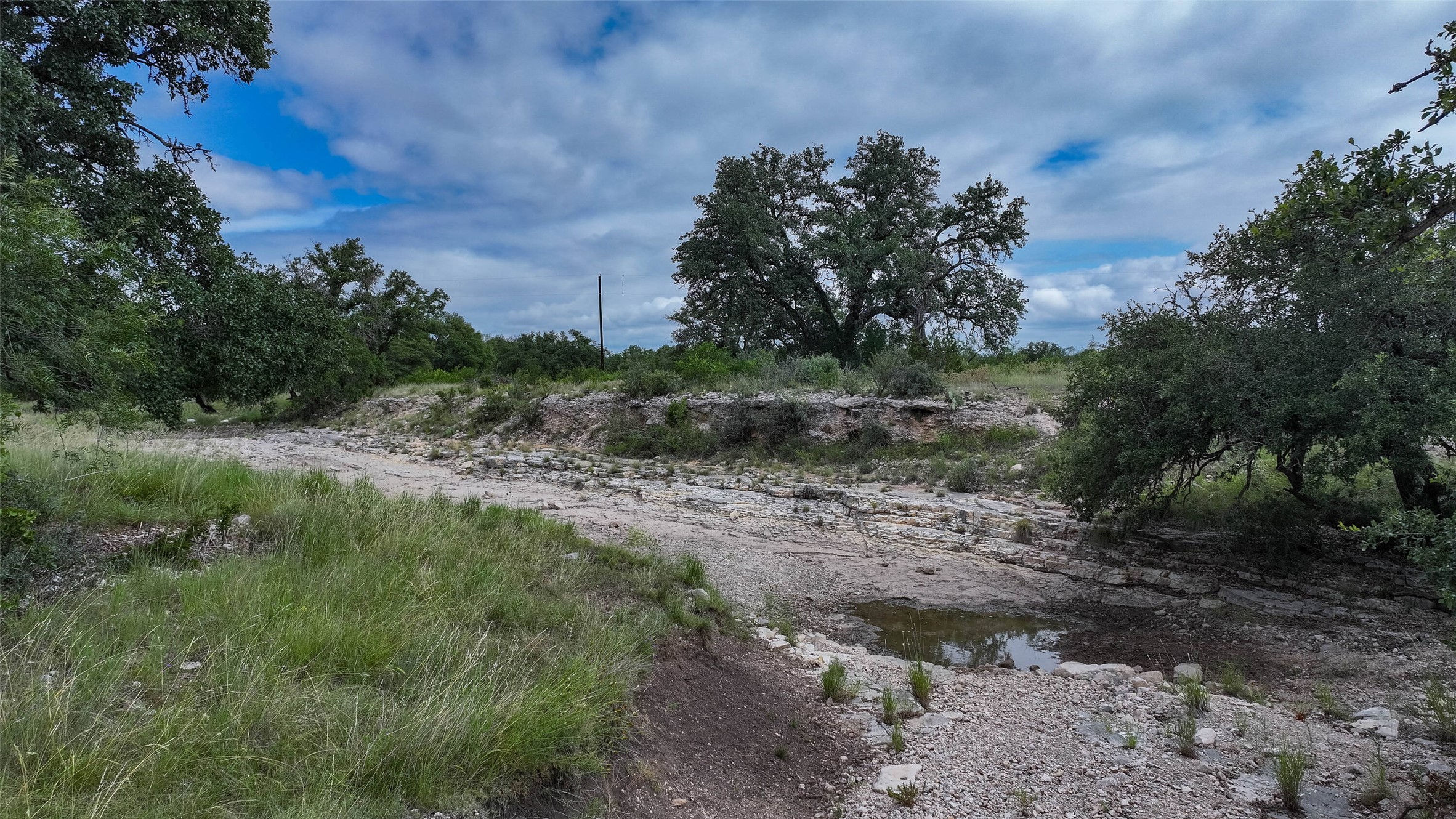 5 Dominion At Oak Ridge Junction, TX 76849 - Photo 11 of 34 Natural land featuring mature trees, varying topography, and a rocky creek bed with a small water presence