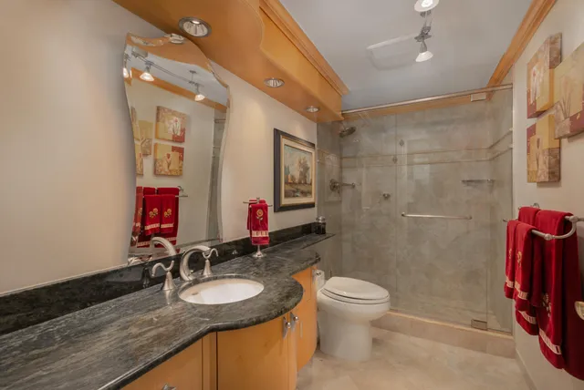 a bathroom with a granite countertop sink mirror vanity bathtub and toilet