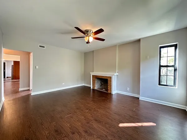 a view of an empty room with window and wooden floor