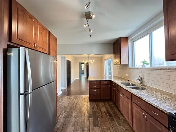 a kitchen with granite countertop stainless steel appliances a refrigerator cabinets and wooden floor