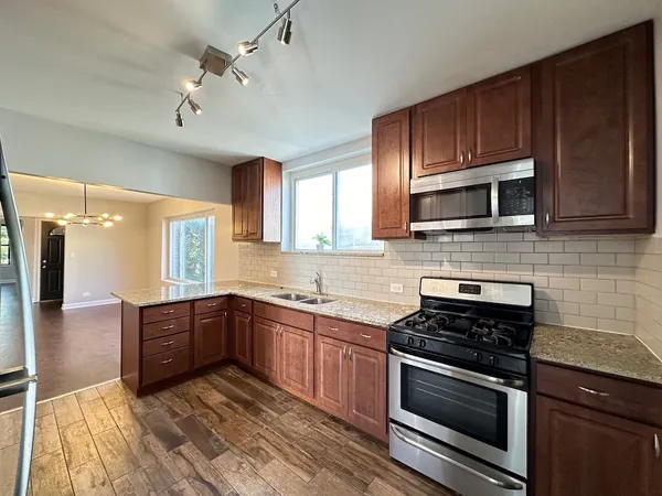 a kitchen with stainless steel appliances granite countertop wooden cabinets stove top oven and sink