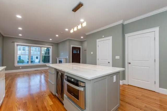 a large kitchen with stainless steel appliances kitchen island a large counter top and wooden floors