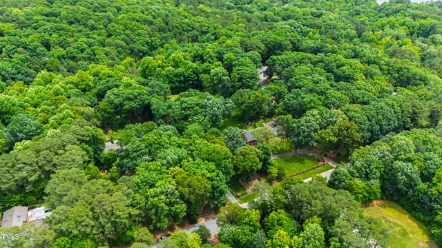 an aerial view of residential house with outdoor space and trees all around