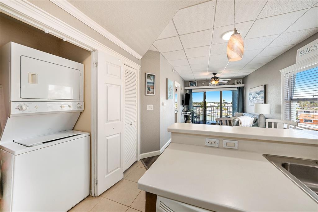 13999 Gulf Boulevard, Unit 406 St. Petersburg, FL 33708 - Photo 14 of 35 a large white kitchen with a refrigerator a stove a sink dishwasher and a dining table with wooden floor