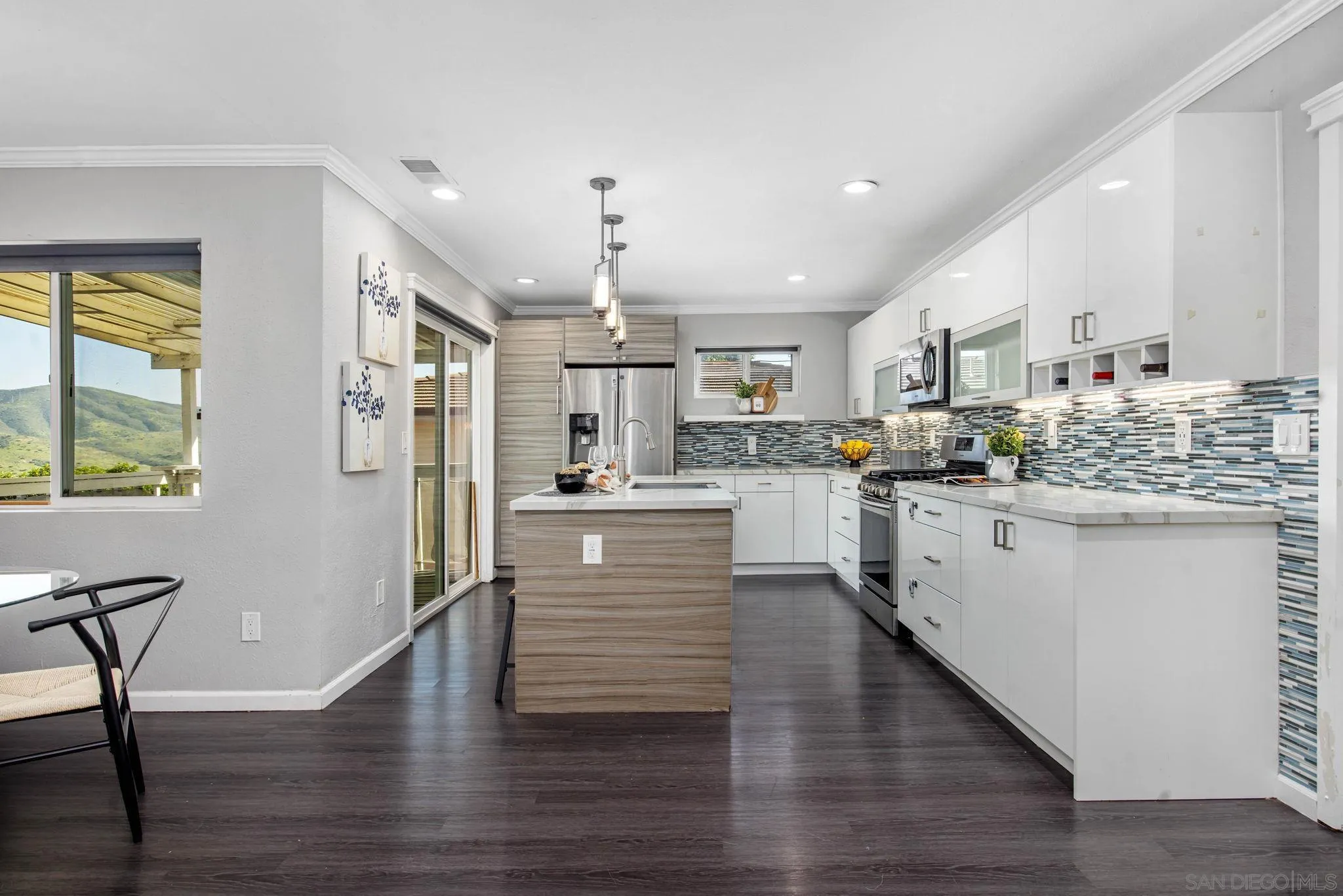 1311 Ramona Avenue Spring Valley, CA 91977 - Photo 4 of 33 a kitchen with stainless steel appliances kitchen island wooden floors and white cabinets
