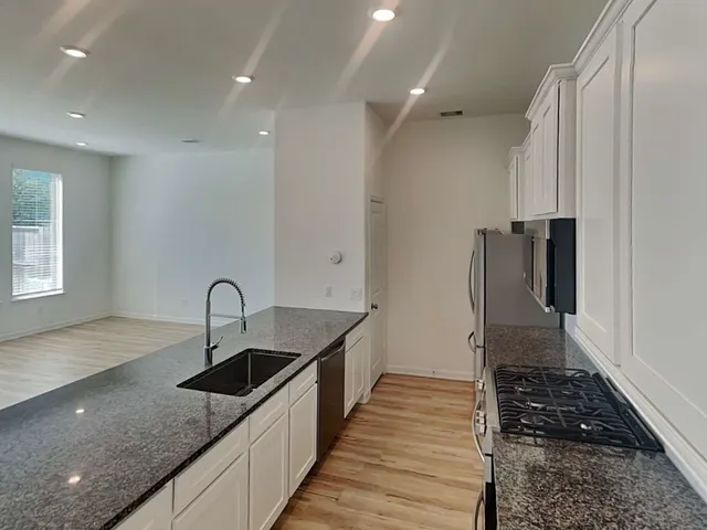 a kitchen with granite countertop a sink and a stove top oven