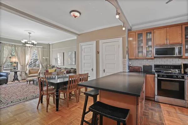 a open kitchen with stainless steel appliances granite countertop a stove top oven a sink dishwasher a dining table and chairs with wooden floor