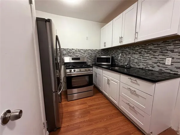 a kitchen with granite countertop white cabinets and stainless steel appliances