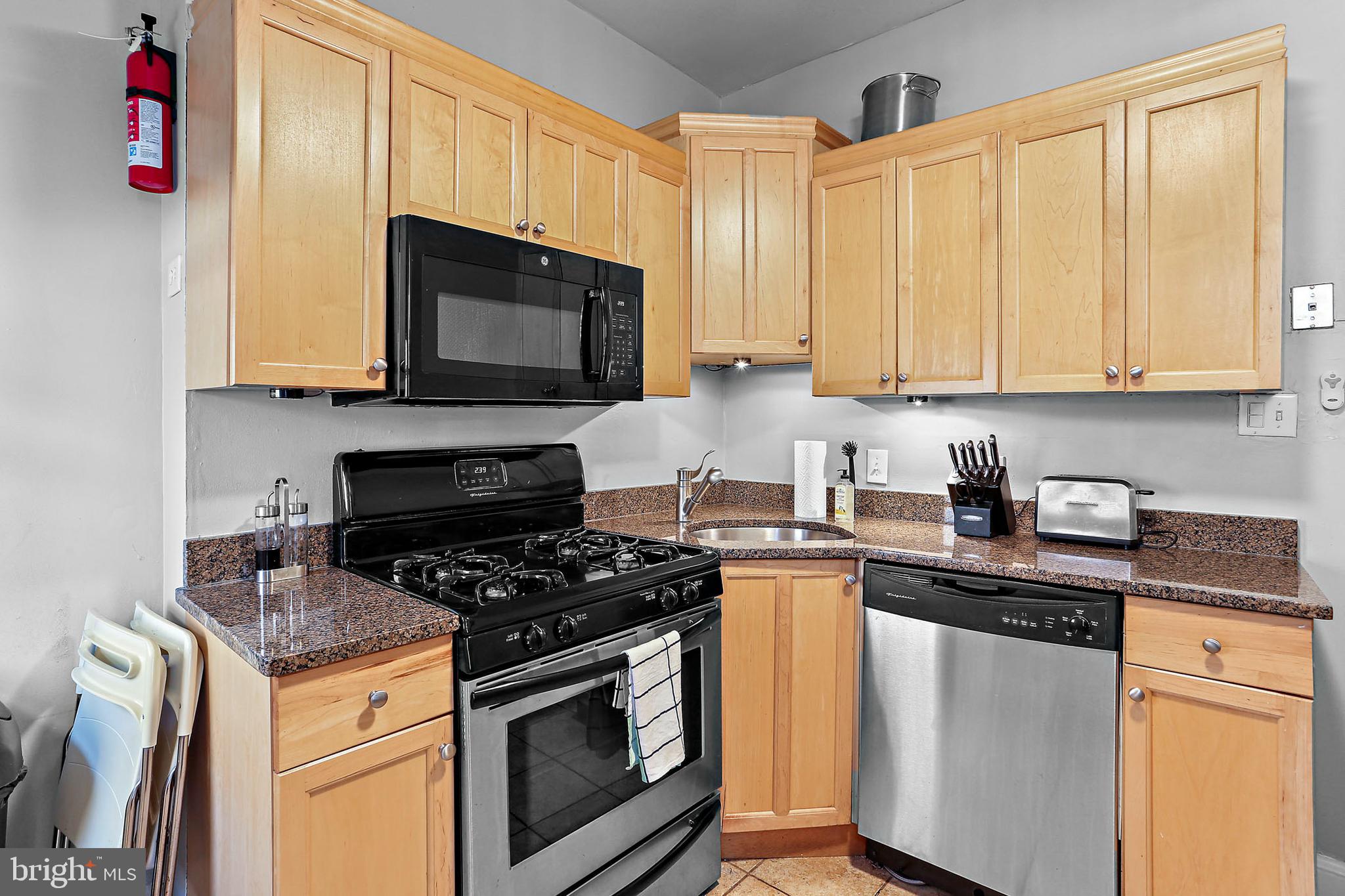 1211 33rd Street Northwest, Unit 1 Washington, DC 20007 - Photo 15 of 18 a kitchen with granite countertop a stove sink and microwave