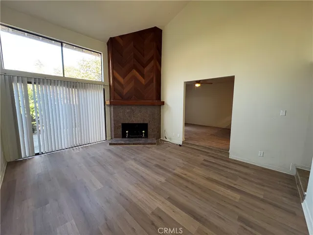 an empty room with wooden floor fireplace and windows