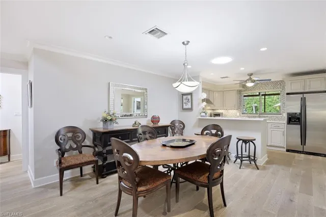 a view of a dining room and livingroom with furniture wooden floor a rug a painting and a chandelier